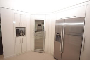Teil einer weißen Küche mit Einbauschränken, Spiegelfront und zweiteiligem Edelstahlkühlschrank